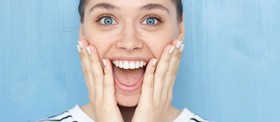 very excited woman with hands to cheeks and mouth open, smiling