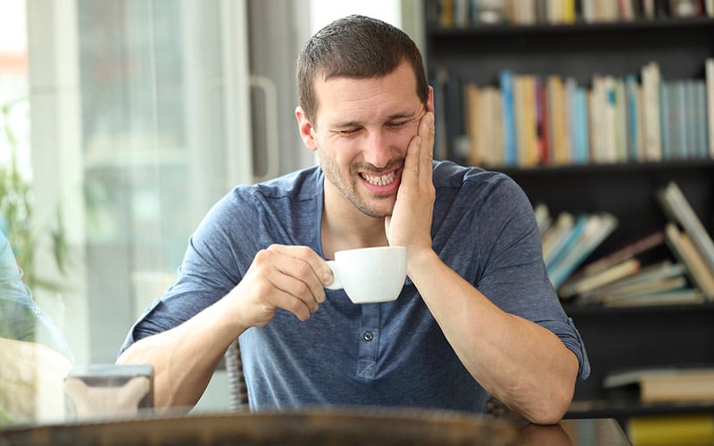 man with toothache drinking coffee