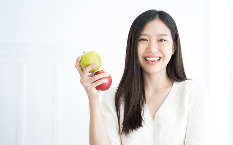 smiling woman holding 2 apples
