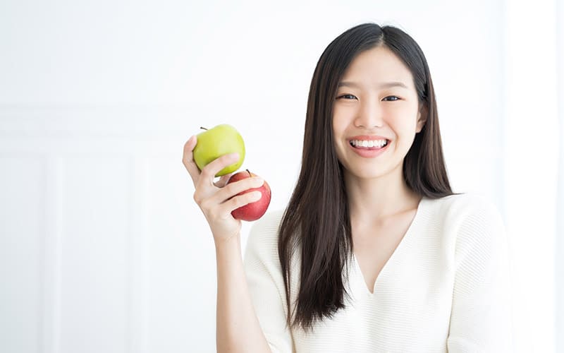 sdc-misc-implants-1 smiling woman holding 2 apples