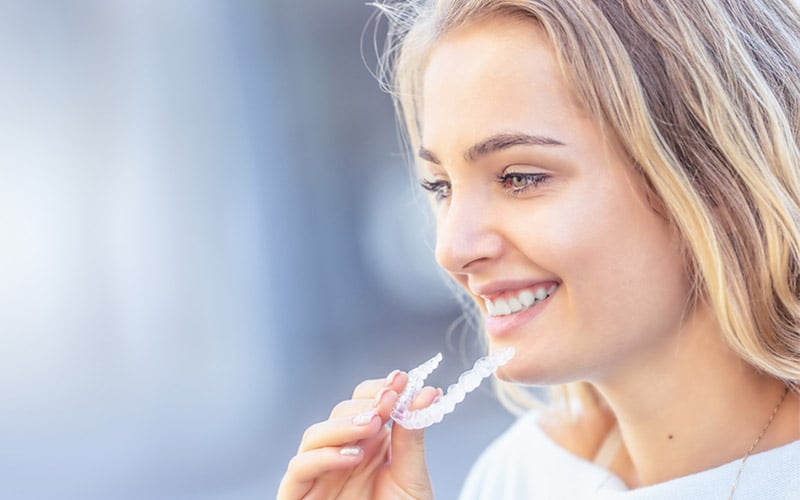 girl holding Invisalign aligner tray