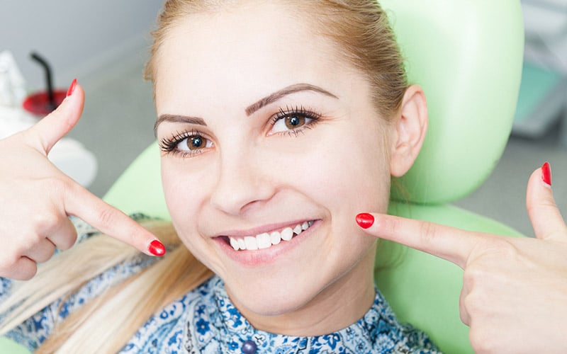 smiling woman pointing at mouth